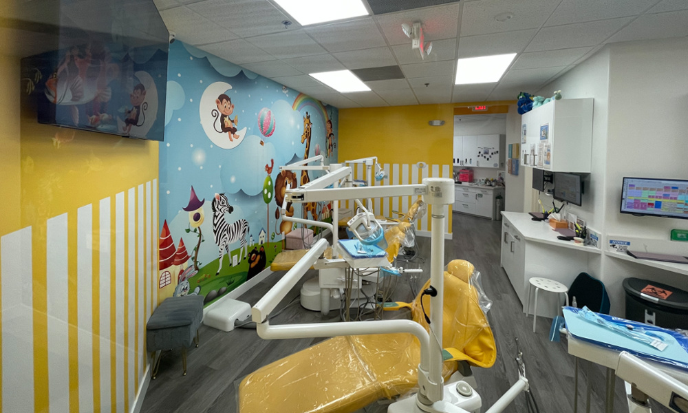Pediatric dental treatment room with colorful animal mural, yellow chairs, and modern dental equipment