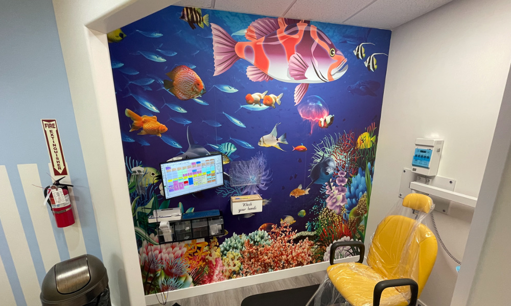 Dental X-ray room with vibrant underwater ocean mural featuring colorful fish and coral reef